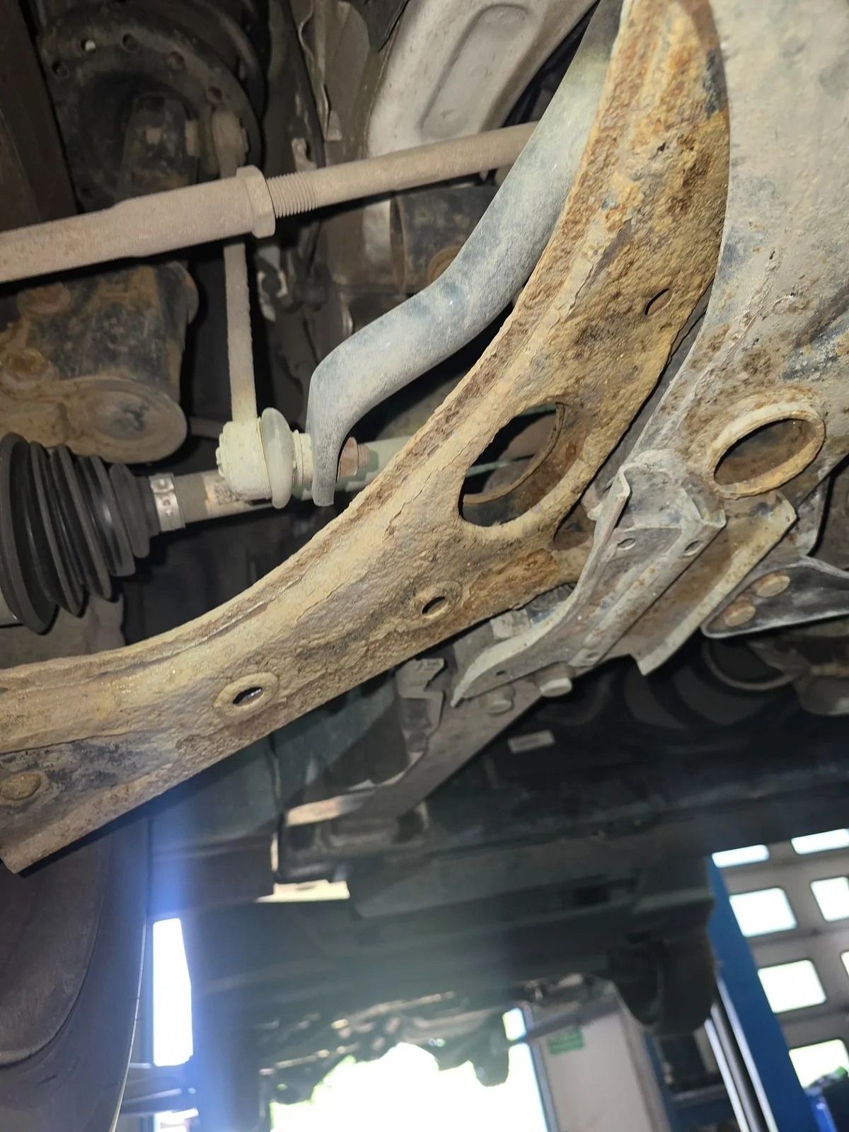 Przedni wahacz z wyraźną korozją widoczną podczas kontroli zawieszenia.